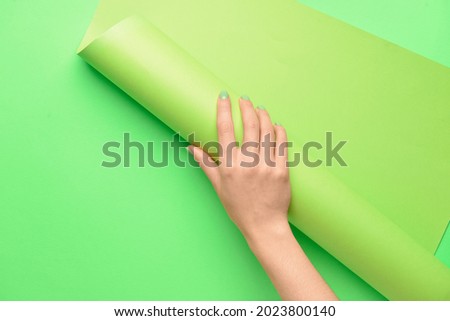 Female hand with paper roll on color background