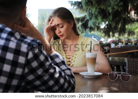 Young woman having boring date with guy in outdoor cafe Royalty-Free Stock Photo #2023817084