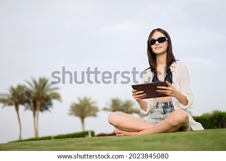 Cut teenager girl using tablet on the background of the beach. Summer vacation concept, studying online with tablet, distance learning, self education, beach work                              