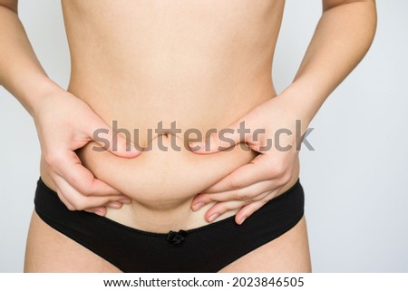 girl holding her belly with her hands on a white background. pregnancy, bloating, excess weight, bowel problems, abdominal and back pain.
 Royalty-Free Stock Photo #2023846505