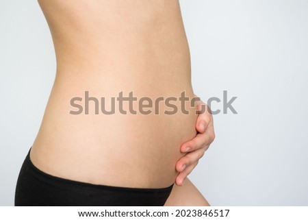 girl holding her belly with her hands on a white background. pregnancy, bloating, excess weight, bowel problems, abdominal and back pain.
 Royalty-Free Stock Photo #2023846517