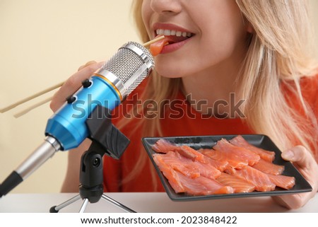 Food blogger eating in front of microphone at table, closeup.