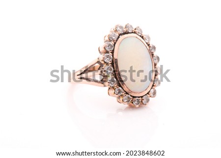 A diamond and opal dress ring, set with an oval cabochon opal within a rub over setting, surrounded with a border of round brilliant-cut diamonds