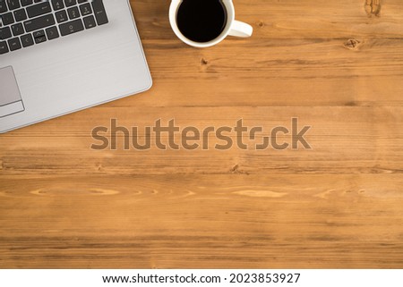Top view photo of laptop and cup of coffee on isolated wooden table background with copyspace