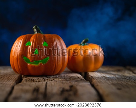 Pumpkins, one of which is in the form of a head with a creepy smile, illuminated by a lantern. Wooden table. Night sky. Halloween. Banner, poster.