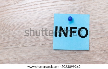 On a light wooden background - a light blue square sticker with the text INFO