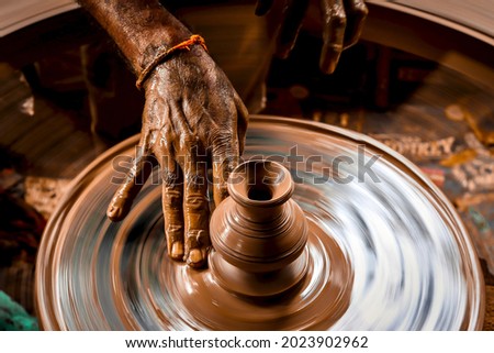 A slow shutter speed shot of a potter hand making a pot from a pottery wheel at Hubli, Karnataka, India. Royalty-Free Stock Photo #2023902962