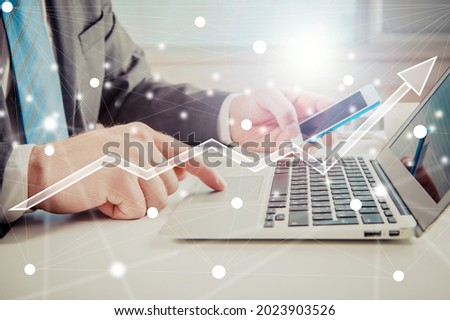 Human hands with smartphone working on laptop computer on office desk