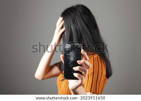 woman showing broken phone screen on gray background