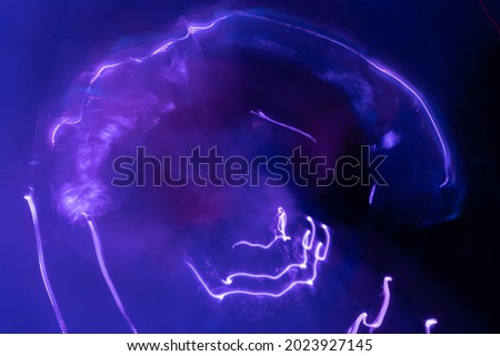 Blue squiggly and circular electricity like light streaks on blue background