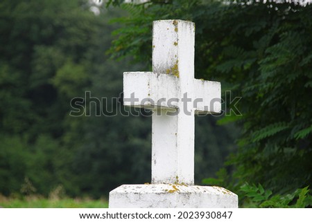 White concrete Christian cross in a field on a background of grass