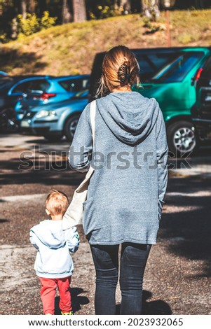 Mother on a walk with baby among cars.