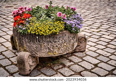 Mixed flower arrangement in a large flower pot, on a cobbled street on the streets of Melsungen, Germany. Street view, travel photo.