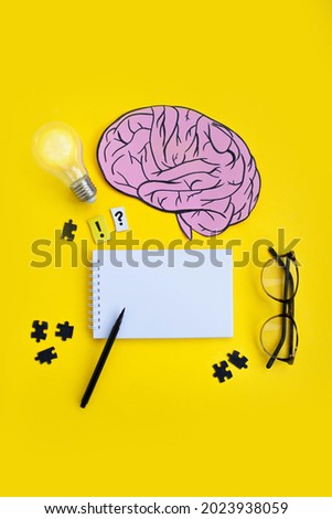 flatlay composition with a drawn brain, a light bulb, a blank notebook and puzzles. copy space. top view