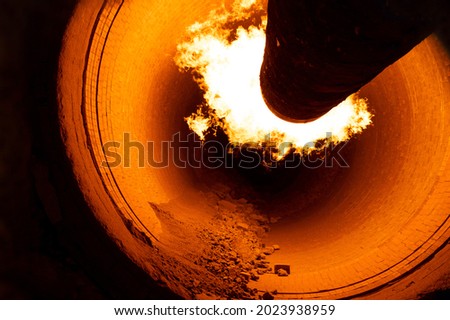 Close up of flame in rotary kiln during heating mode in cement plant Royalty-Free Stock Photo #2023938959