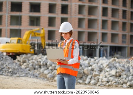 Portrait of female construction engineer in casque using laptop at construction site. Royalty-Free Stock Photo #2023950845