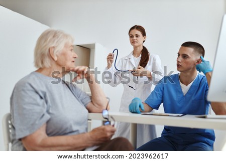 a nurse with a stethoscope in her hands next to a doctor diagnosing a patient