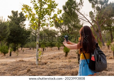 Young caucasian girl backwards with mobile in the park