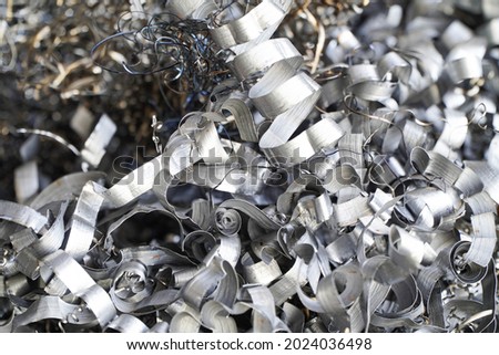 Steel scrap materials recycling. Aluminum chip waste after machining metal parts on a cnc lathe. Closeup twisted spiral steel shavings. Small roughness sharpness, Royalty-Free Stock Photo #2024036498