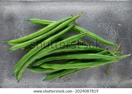 Several organic ripe green beans on a metal tray, close-up, top view.
