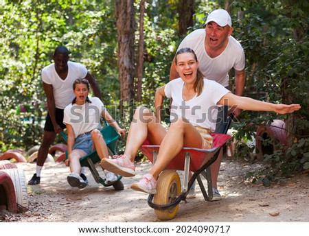 Men drive their girls in garden wheelbarrows. Funny amusement park amusement park. High quality photo