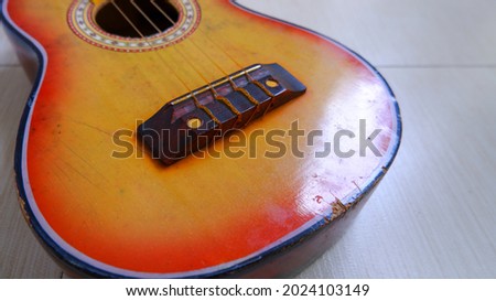 Yellow body of miniature acoustic guitar, focused on the bridge