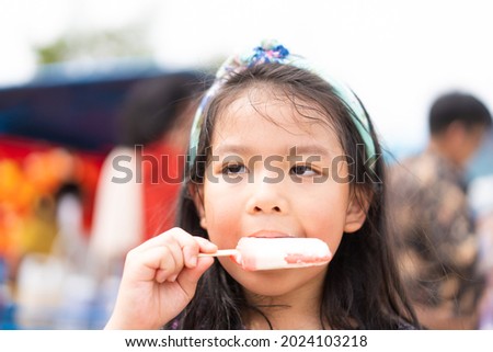 Asian child girl feeling happy while eating homemade avocado ice cream bar on a summer day. smiling little girl eating ice cream. Asian Korean kids eat ice cream bars.
