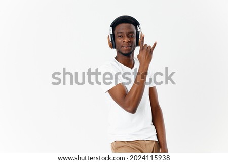 smiling African American with headphones listening to music gesturing with hand light background