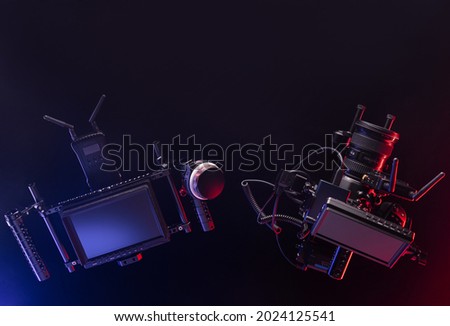 Top view of professional videographer equipment with digital camera, cage, lens and director's monitor with focus control. Top view on a black table background. 