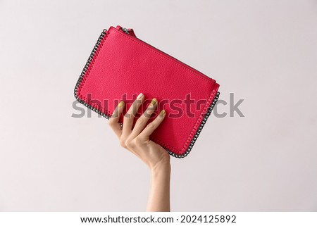 Female hand with beautiful manicure and bag on light background