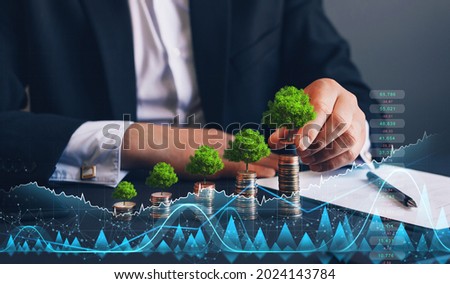 Businessman holding coin with tree growing on money coin stack and digital growth graph. Green business growth. Finance sustainable development. 