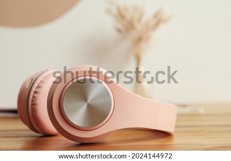 Modern headphones on wooden table near color wall, closeup