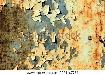 Old paint damaged background close-up. Metal surface with rust and cracked yellow paint. Dirty yellow metal crack surface texture background 