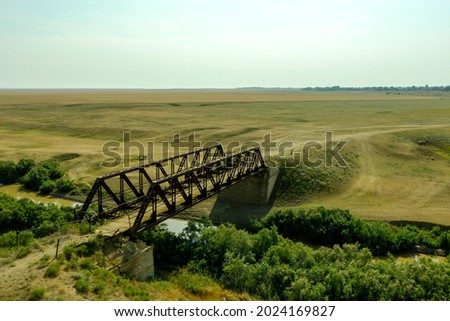 an old iron bridge over a river in the steppe on a country road a picture from a drone. High quality photo