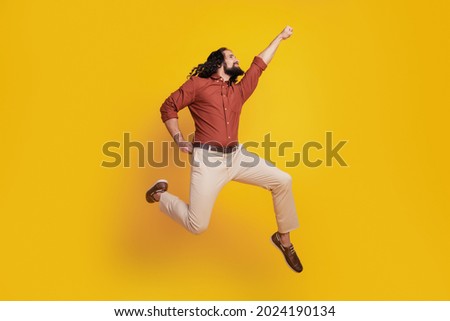 Portrait of superhero guy jump raise fist fly save world on yellow background