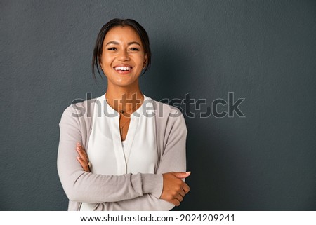 Beautiful mid adult african american woman standing on grey wall with crossed arms. Mature indian woman isolated on gray background. Portrait of smiling hispanic lady looking at camera. Royalty-Free Stock Photo #2024209241
