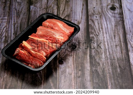 Raw beef meat in a black plastic cointainer. Opened black plastic tray with raw cut meat