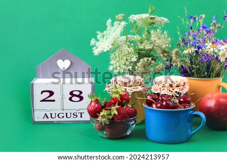 Calendar for August 28 : the name of the month of August in English, cubes with the number 28, bouquets of wild flowers, jars of jam, strawberries and cherries in cups, green background