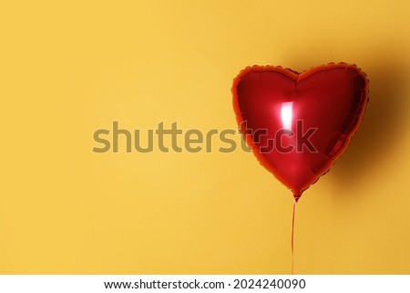 Festive heart shaped balloon on yellow background. Space for text