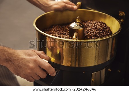 Senior man using modern coffee roaster, closeup