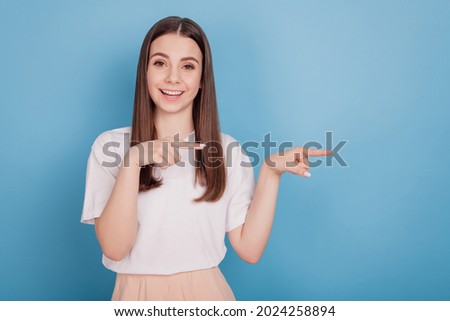 Portrait of adorable cheerful nice lady forefingers direct empty space on blue background