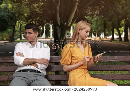 Young woman with smartphone ignoring her boyfriend in park. Boring date Royalty-Free Stock Photo #2024258993