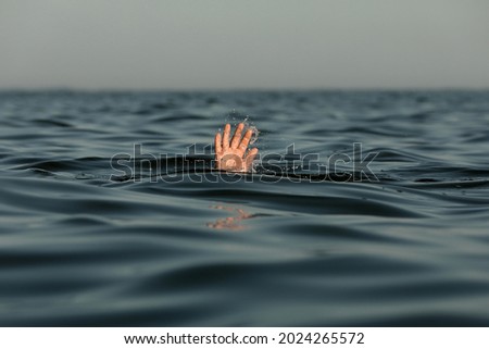 Drowning man reaching for help in sea Royalty-Free Stock Photo #2024265572