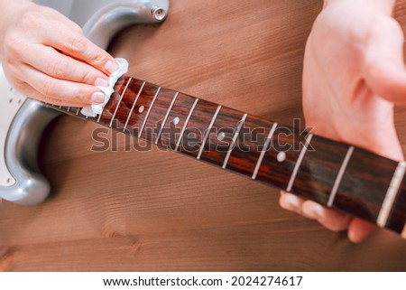 Guitar master polishing fretboard of electric guitar with cloth Royalty-Free Stock Photo #2024274617