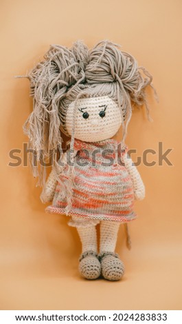 toy doll, knitted by hand from different yarns, on an orange background