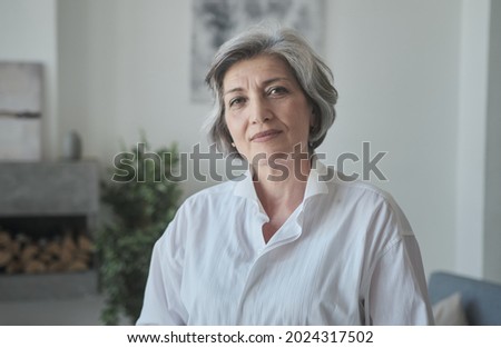 Strong senior mature old businesswoman looks seriously at the camera. Portrait of the Chief Executive in a modern house. Condifent stylish female CEO leader. Royalty-Free Stock Photo #2024317502