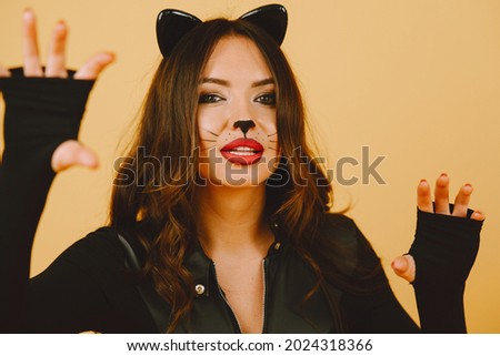 Woman with cat makeup and ears on color background