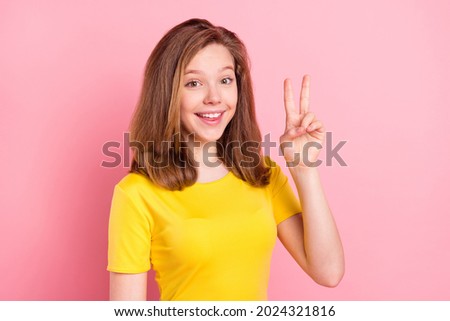 Photo of young attractive girl happy positive smile show peace cool v-sign isolated over pink color background