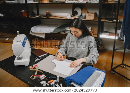 Professional young female tailor working in workshop