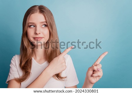 Portrait of curious reliable girl show finger empty space look side advice choice on blue background